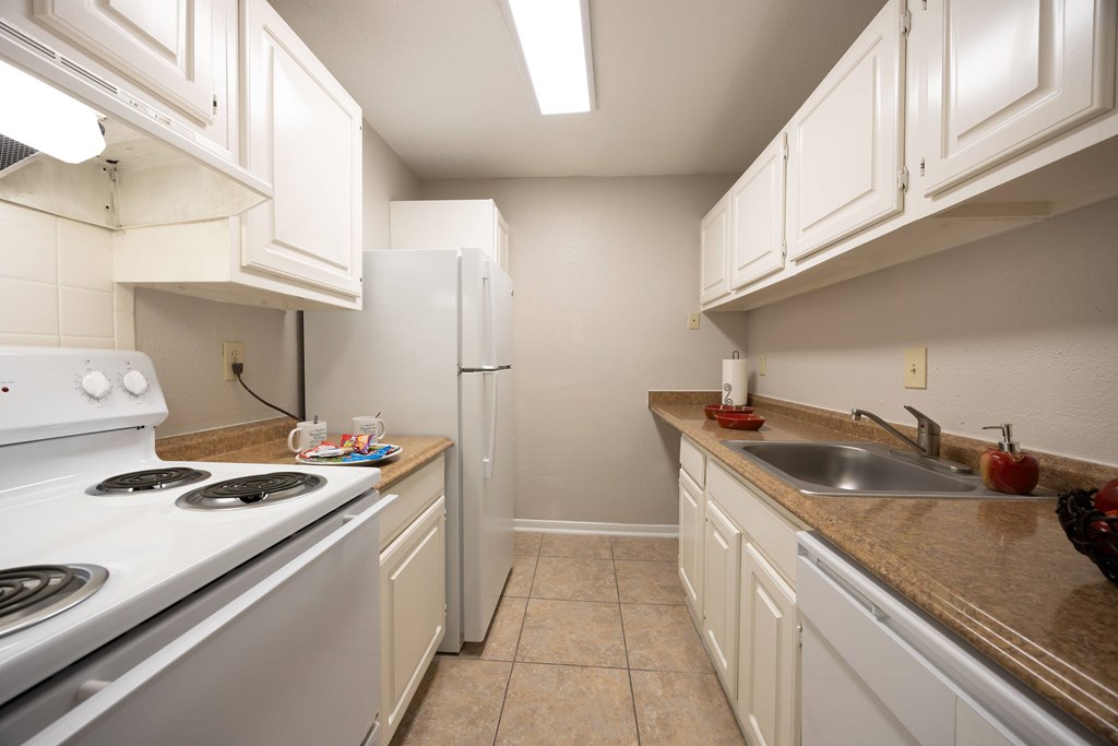 A kitchen with white cabinets and a stove top oven.
