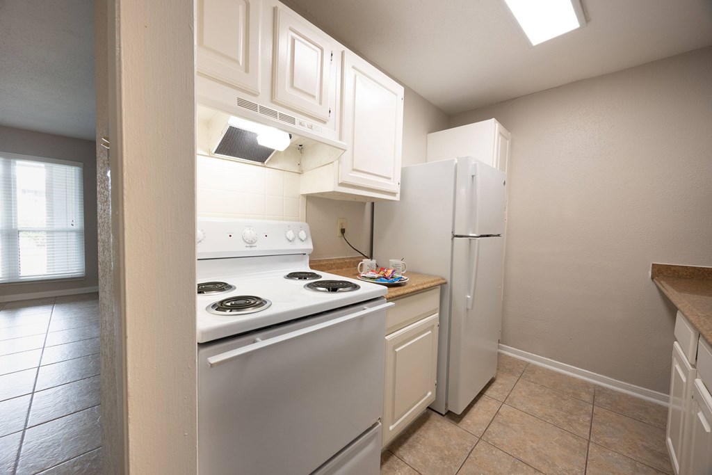 A kitchen with a stove, refrigerator, and cabinets.