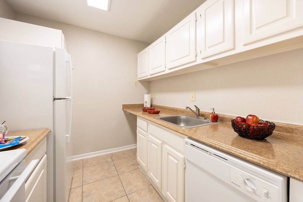 A kitchen with white cabinets and appliances.