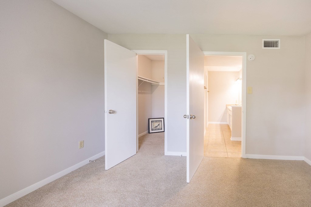 A room with a white door and a carpeted floor.