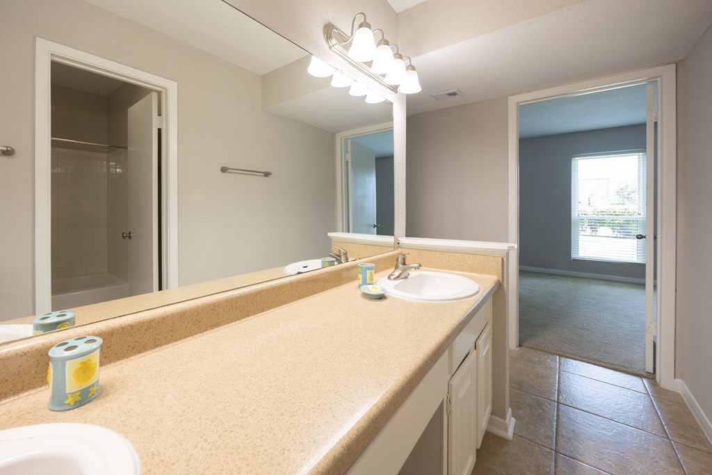 A bathroom with a tan counter top and a white sink.