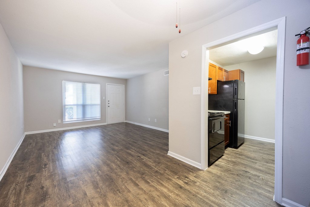 A room with a wooden floor and a black fridge.