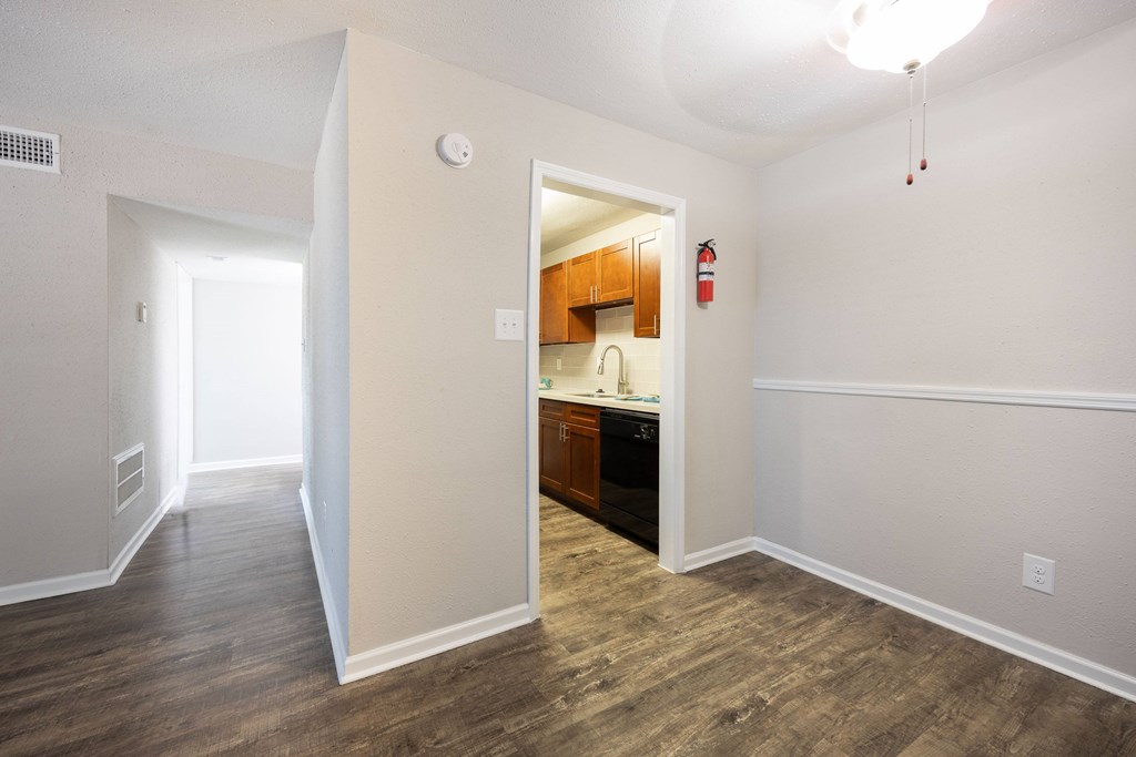A room with a kitchenette and a wood floor.