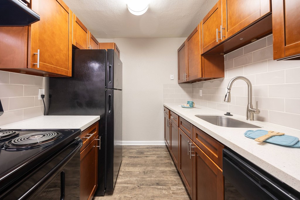 A kitchen with black appliances and wooden cabinets.