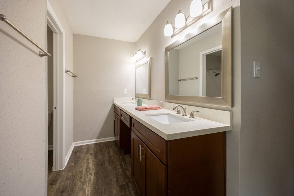 A bathroom with a white sink and brown cabinets.