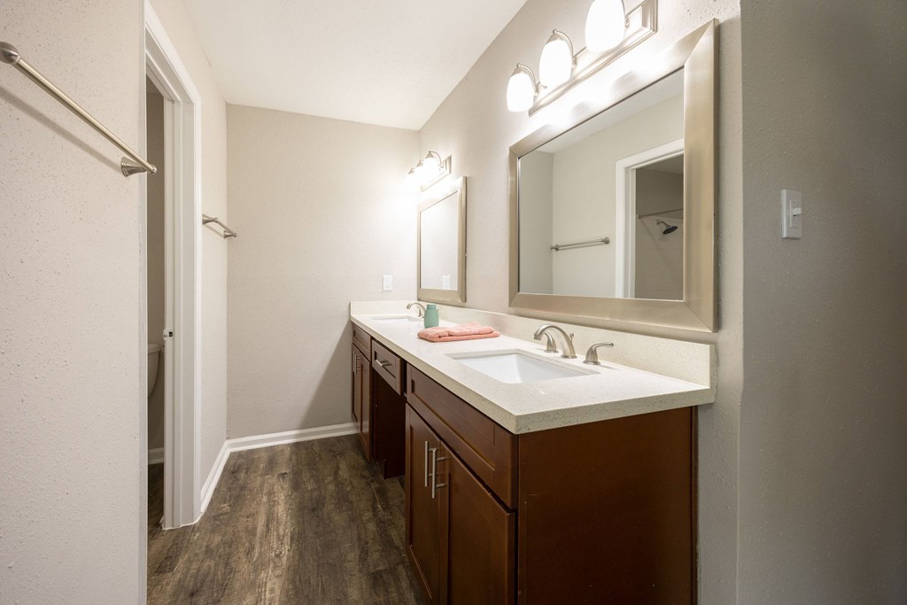 A bathroom with a white sink and brown cabinets.