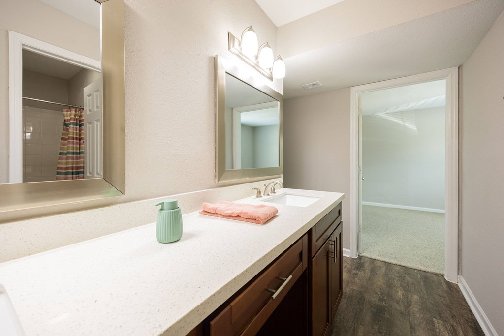 A bathroom with a sink, mirror, and a green vase.