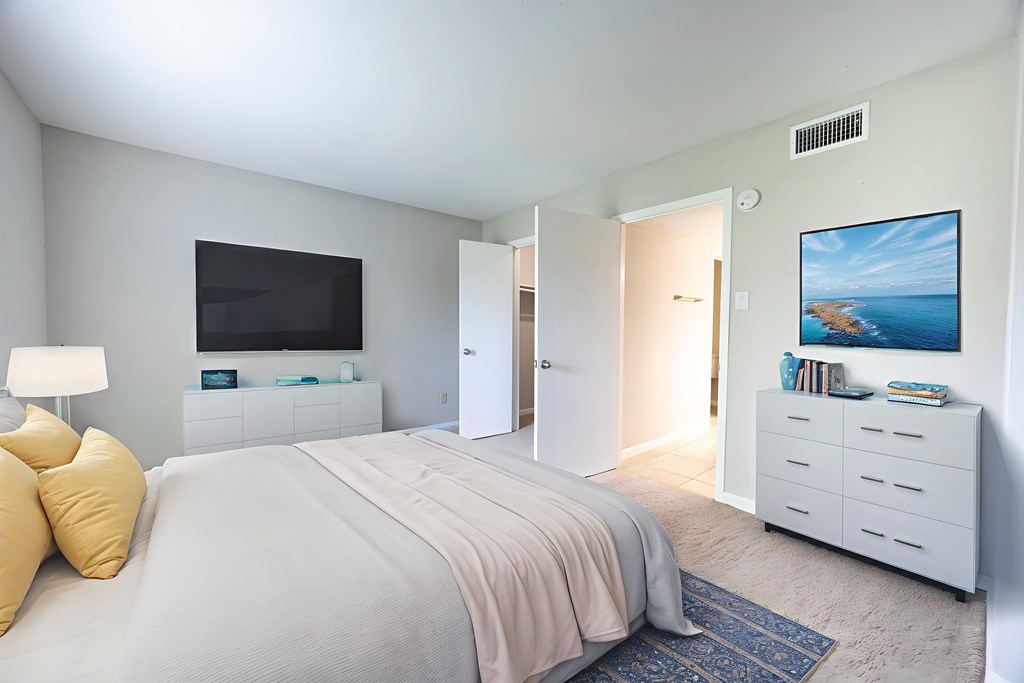A bedroom with a large bed and a television on the wall.