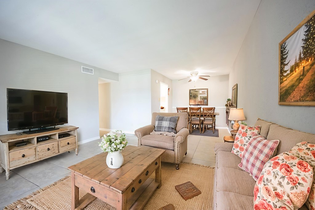 A living room with a couch, chairs, and a television.