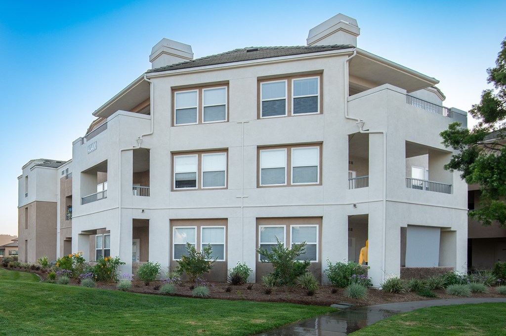 A large, modern apartment building with a pond in front.