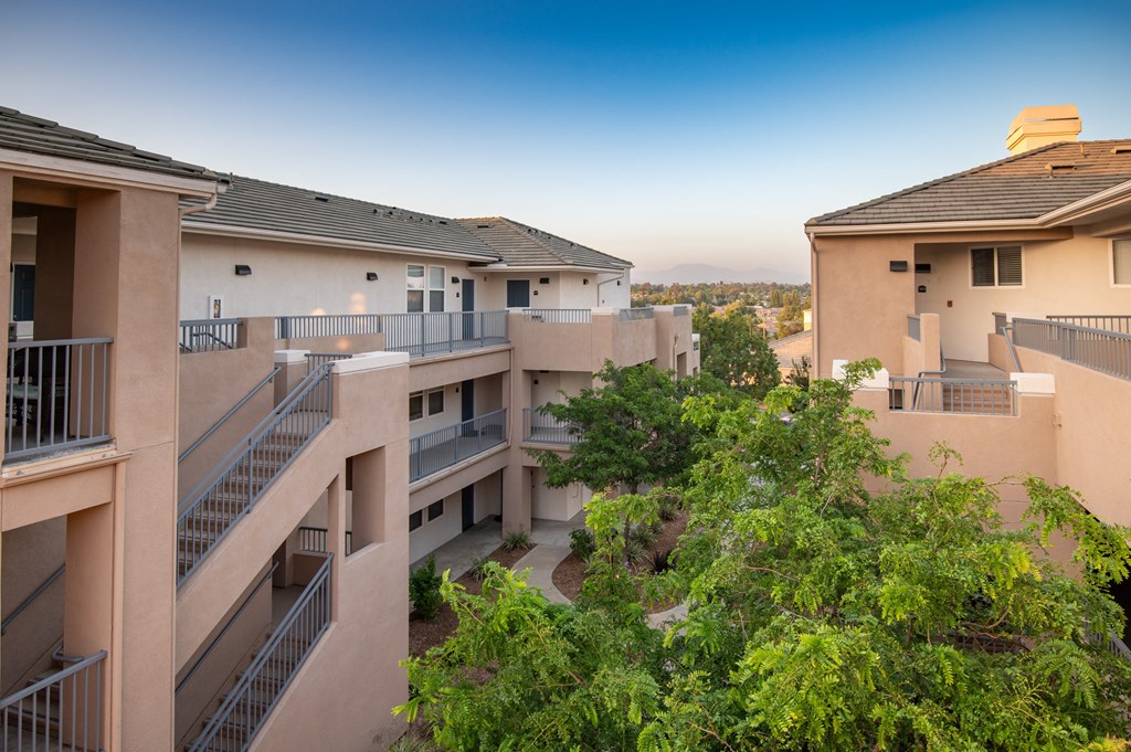 Apartment complex with balconies and trees in the foreground.