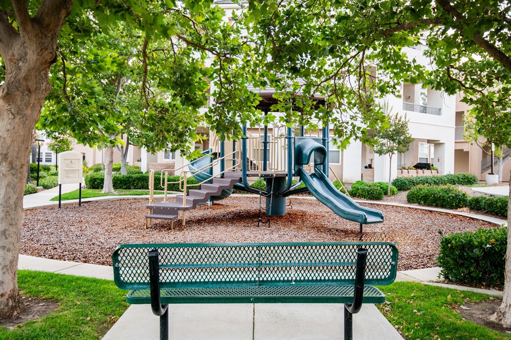 A playground with a green slide and a bench.