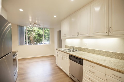 A kitchen with white cabinets and a granite countertop.