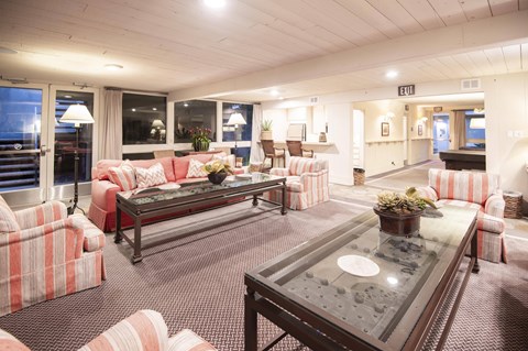A living room with a glass coffee table and striped couches.