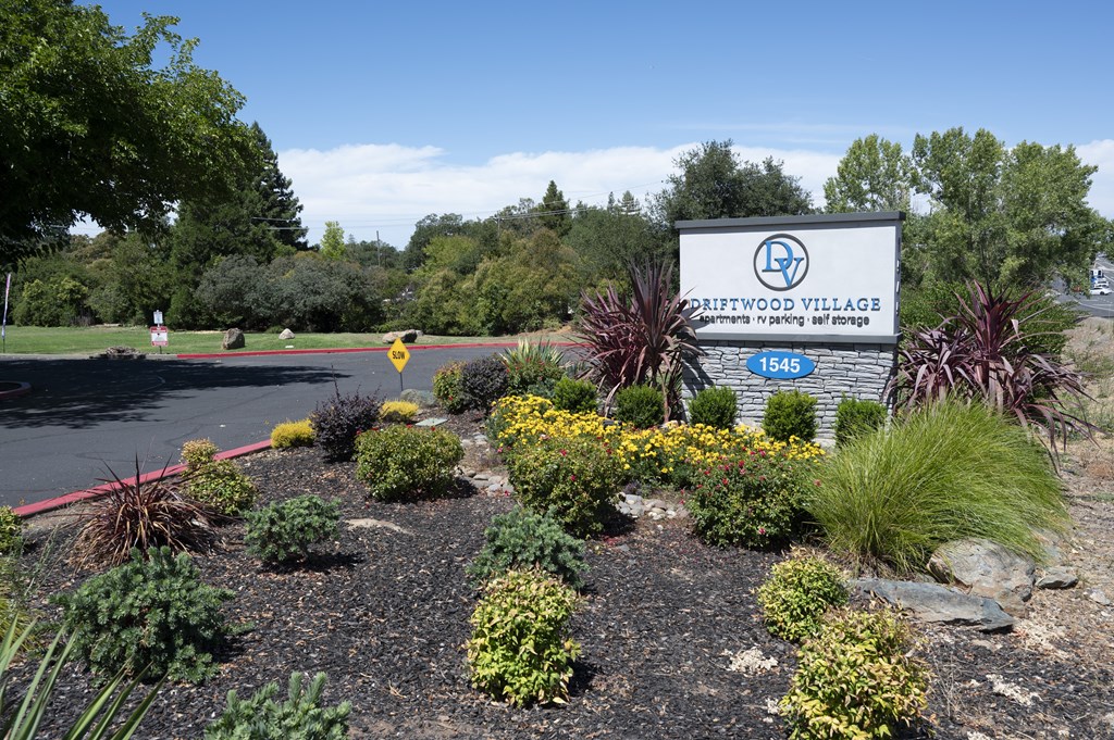 A sign for Griffithwood Village is surrounded by plants and flowers.