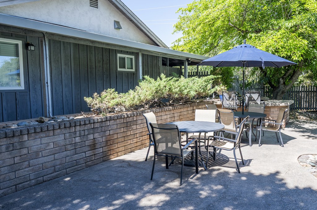 A patio with a table and chairs and an umbrella.