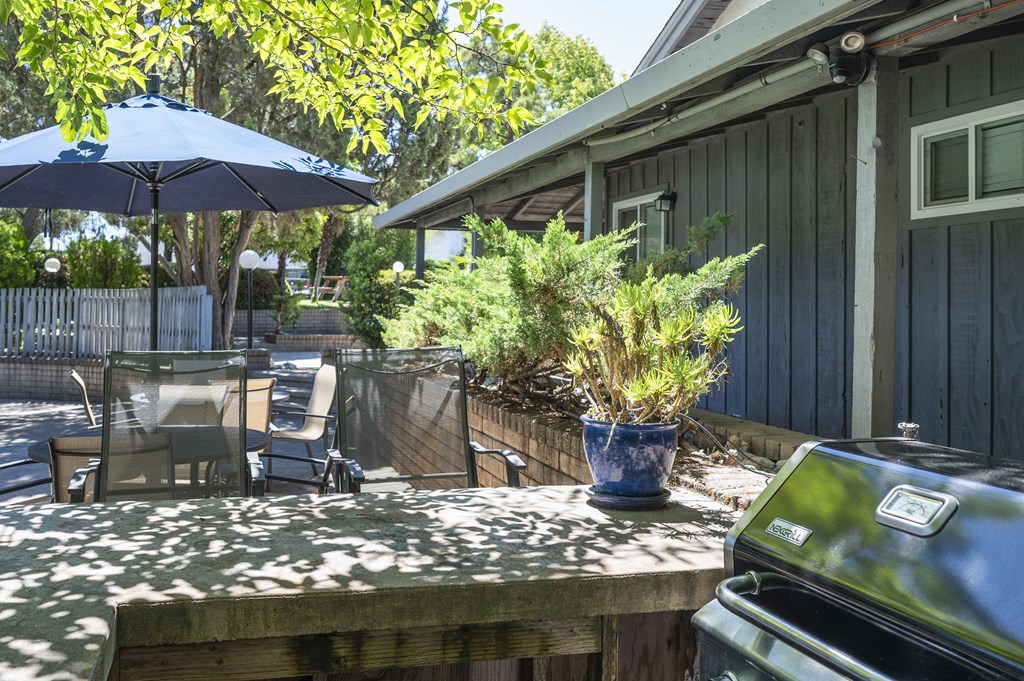 A blue umbrella is on a table with chairs under it.