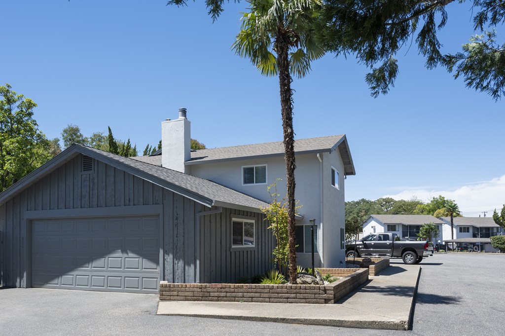 A house with a garage and a tree in front.