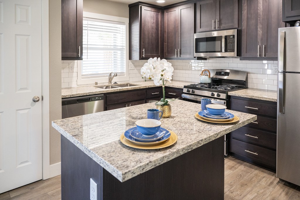 A kitchen with a granite countertop and modern appliances.
