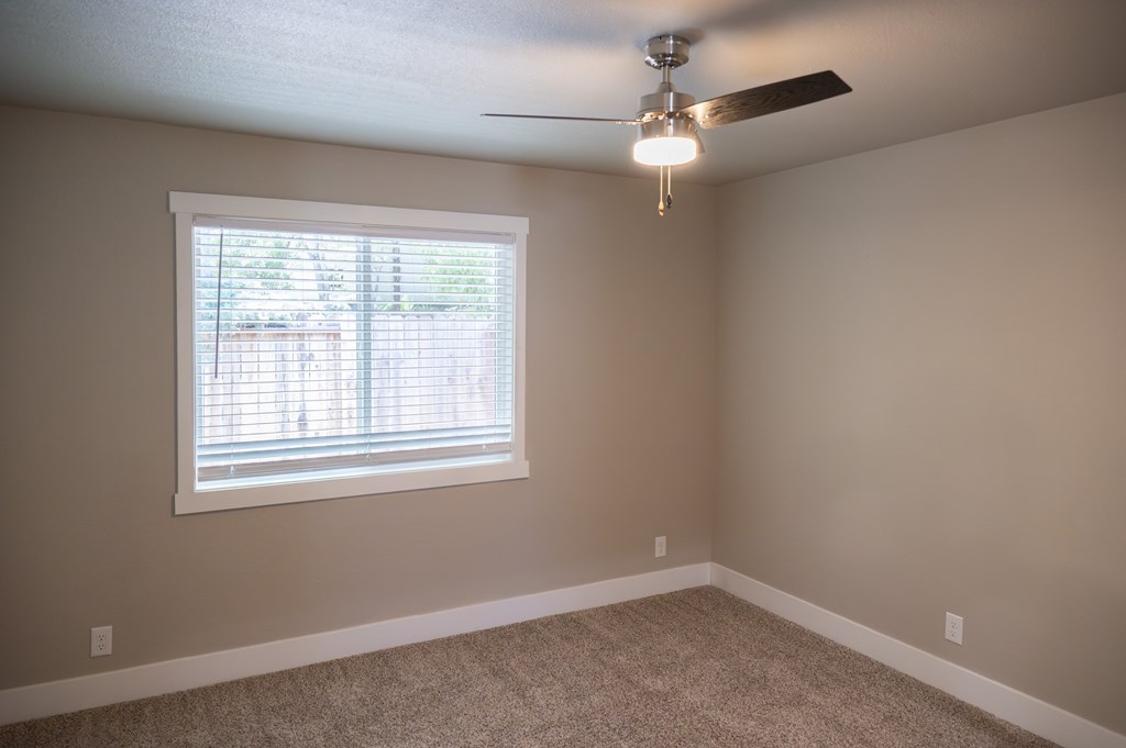 A room with a ceiling fan and a window with blinds.
