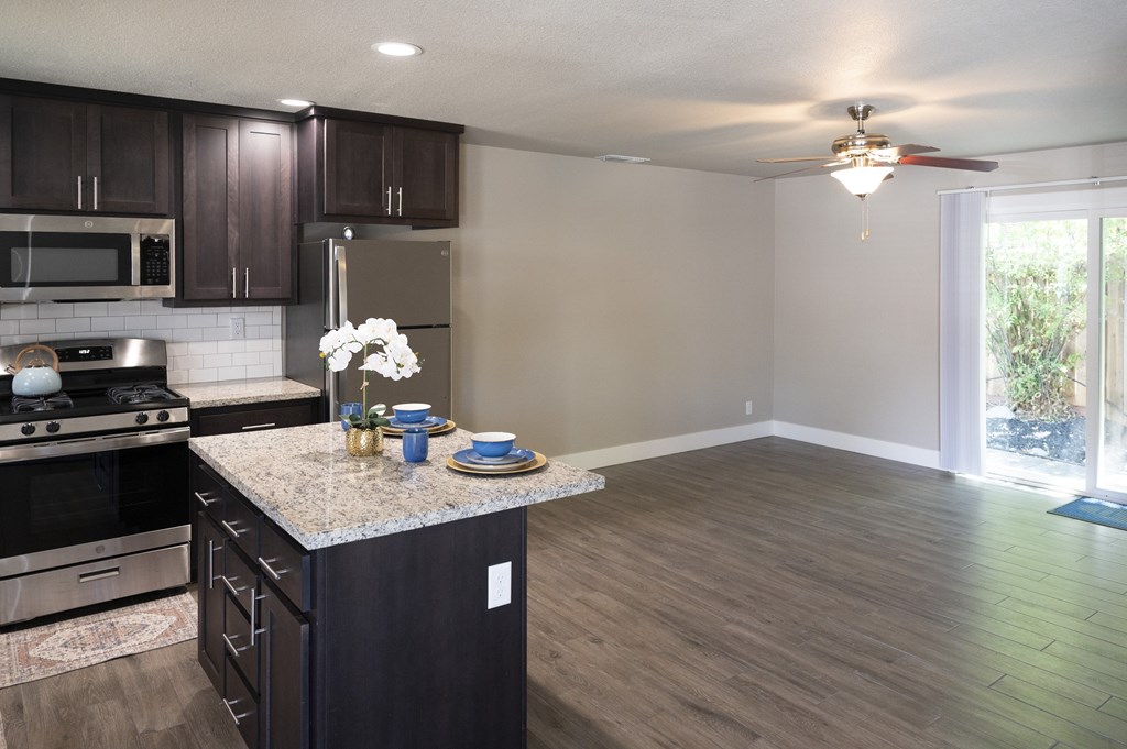 A kitchen with dark wood cabinets and a granite countertop.