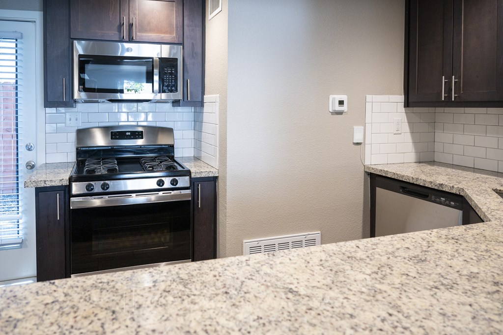 A kitchen with a granite countertop and a stove top oven.