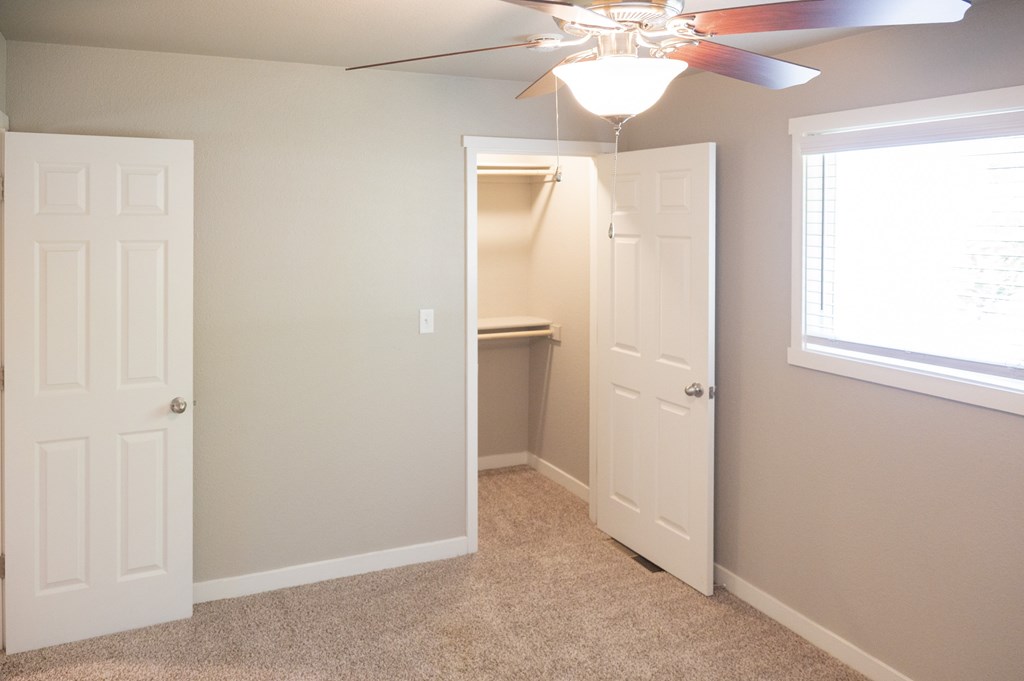 A room with a ceiling fan and two doors.