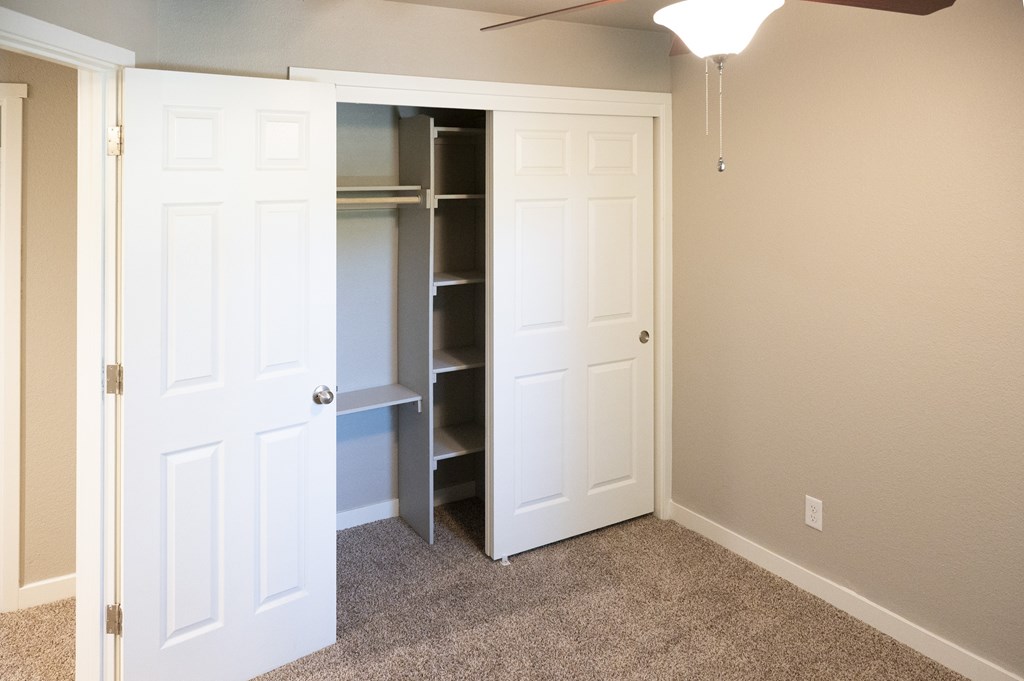 A white closet with a bench and a fan.