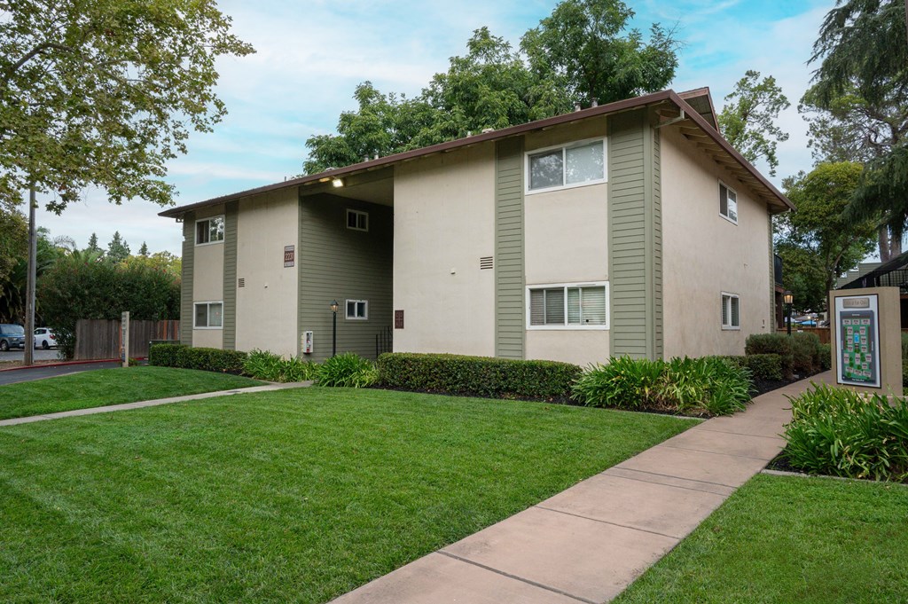 A beige apartment building with a green lawn in front.