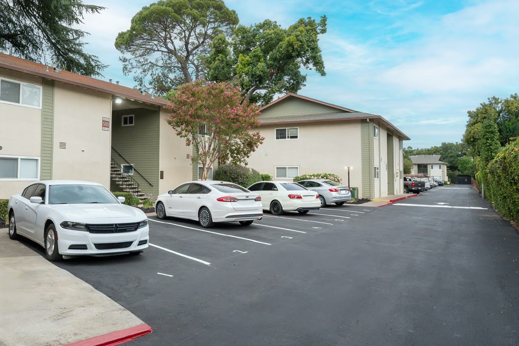 A white car is parked in a parking lot in front of a building.
