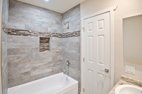 A bathroom with a white tub and a white door.