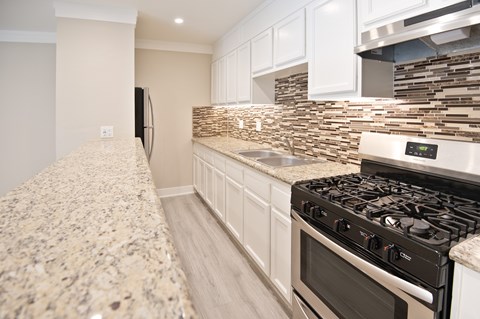 A kitchen with a granite countertop and a stove top oven.
