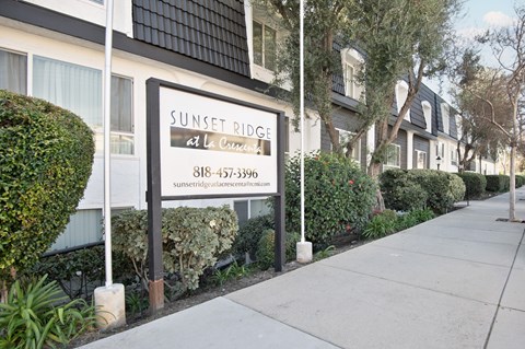 A sign for Sunset Ridge at La Crescent is displayed in front of a building.