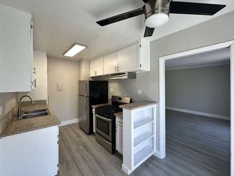 A kitchen with a black fridge and stove top oven.
