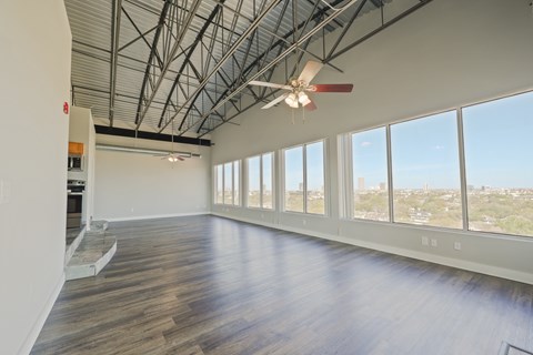 A spacious room with a ceiling fan and large windows overlooking a cityscape.