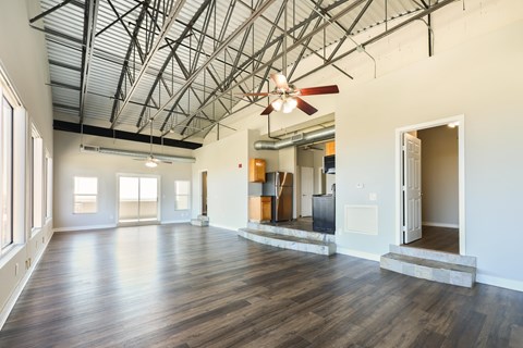 A large empty room with wooden floors and a ceiling fan.