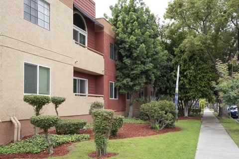 Apartment building with a red brick facade and a green lawn in front.