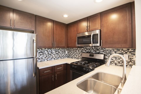 A kitchen with brown cabinets and a stainless steel refrigerator.