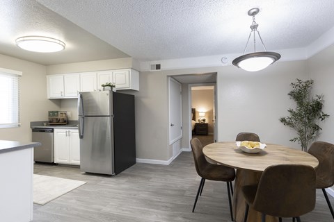 A kitchen with a table and chairs in the foreground and a refrigerator in the background.