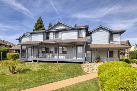 A large, two-story house with a grey exterior and a brown roof.