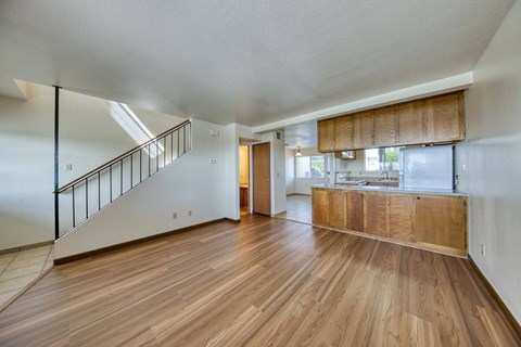 A spacious room with wooden floors and a staircase.