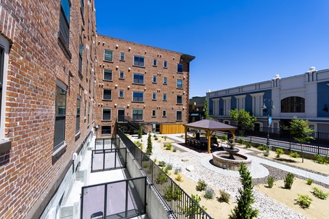 A courtyard with a fountain and a gazebo is surrounded by brick buildings.