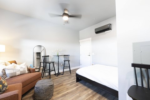 A bedroom with a bed, a couch, and a ceiling fan.