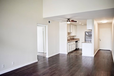 A kitchen with white cabinets and a refrigerator is visible from the living room.