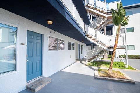 A blue door is on the left side of a white building.