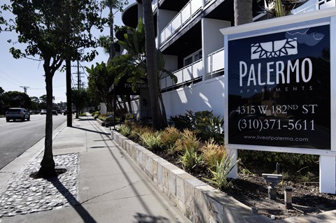 A sign for Palermo Apartments is displayed on a sidewalk.