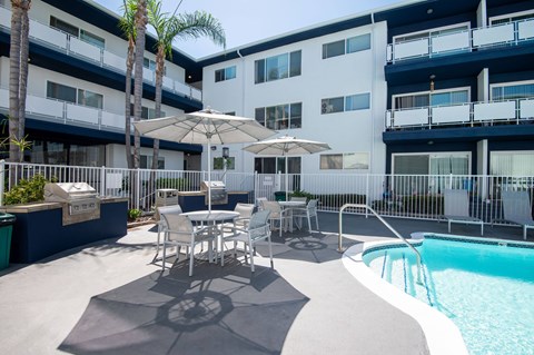 A pool area with a table and chairs and a palm tree.
