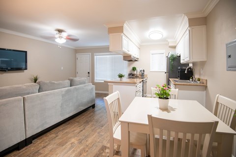 A well-lit, spacious kitchen and living room with a dining table set for four.