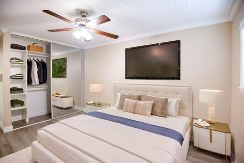 A bedroom with a large bed and a flat screen TV mounted on the wall.