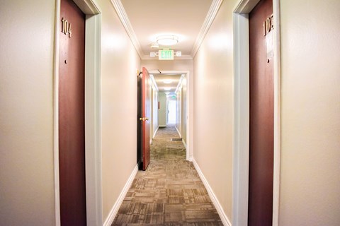 A long hallway with doors on both sides and a green exit sign above.